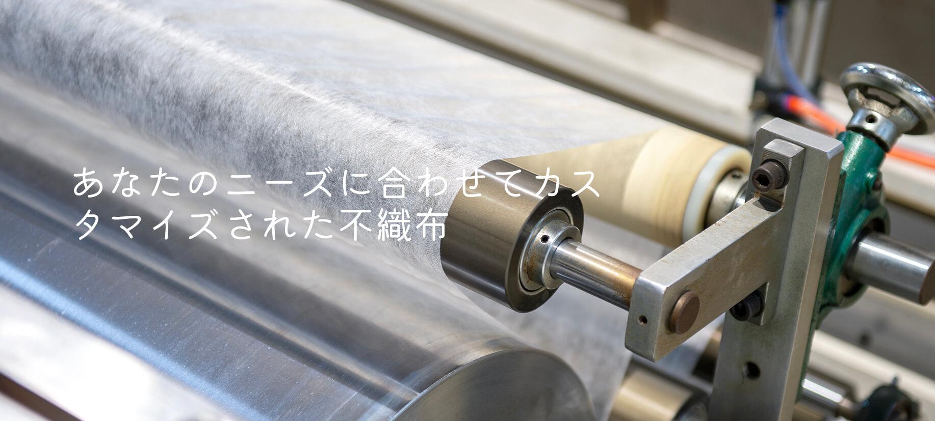 白い不織布材料を処理する製造機械のクローズアップ